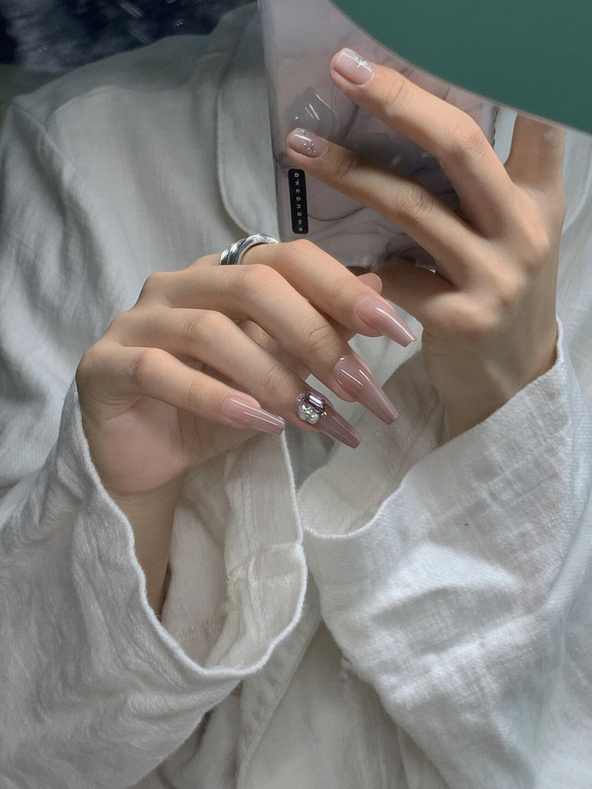 Nude long coffin nails with pearl and gem nail accents.