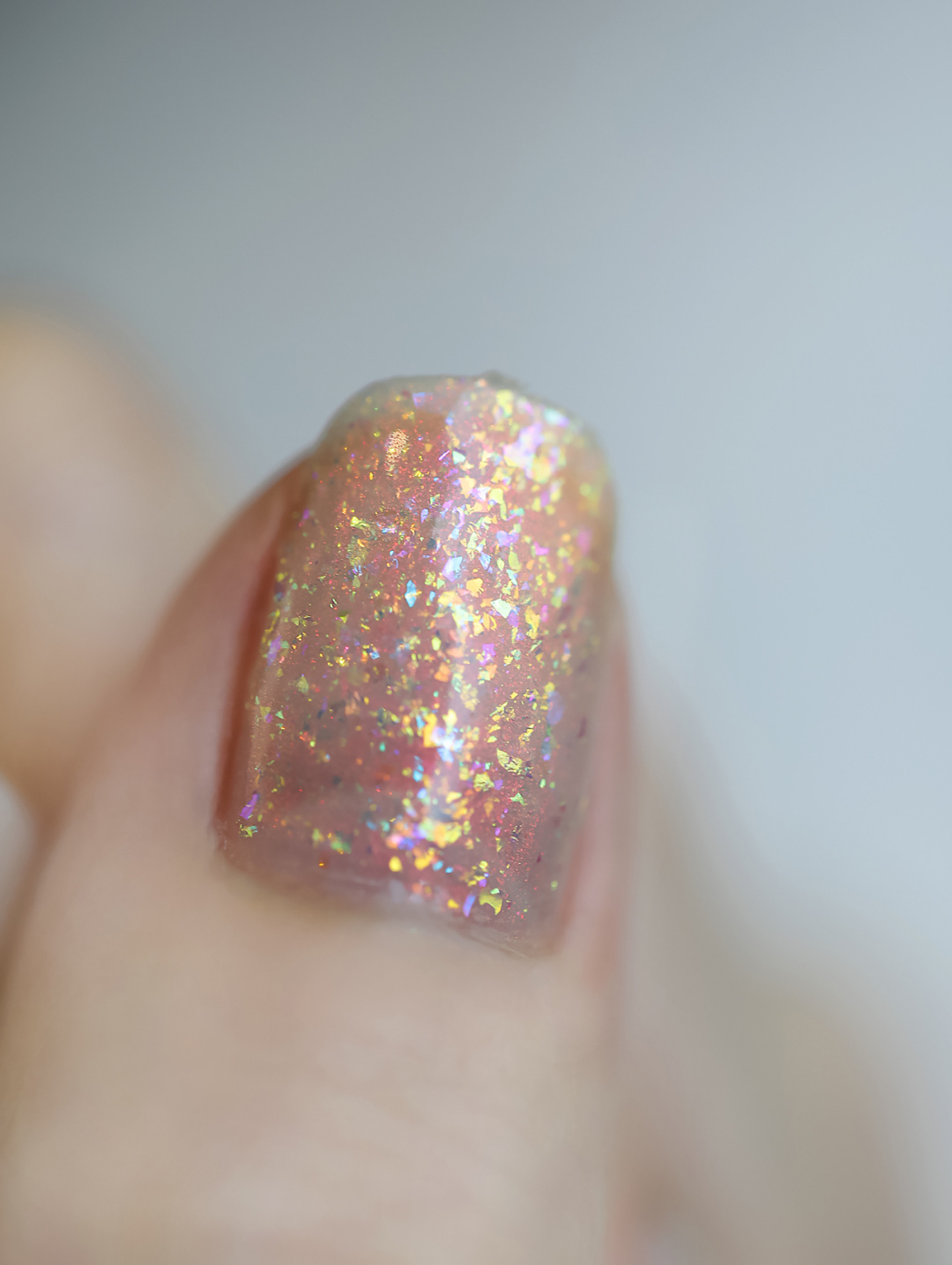 Pink short square nail with iridescent gold glitter flakes.