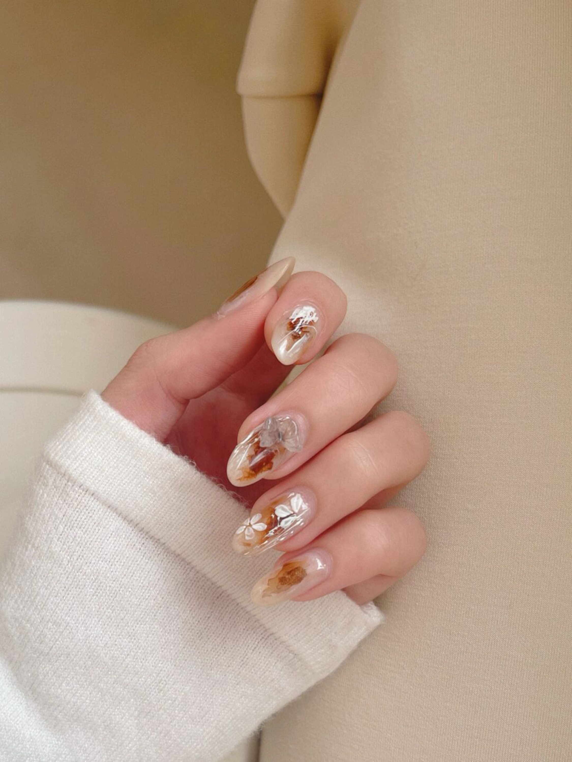 Beige Floral Almond Nails shown as a nail art design with beige, floral, elegant, flower, almond and medium details.