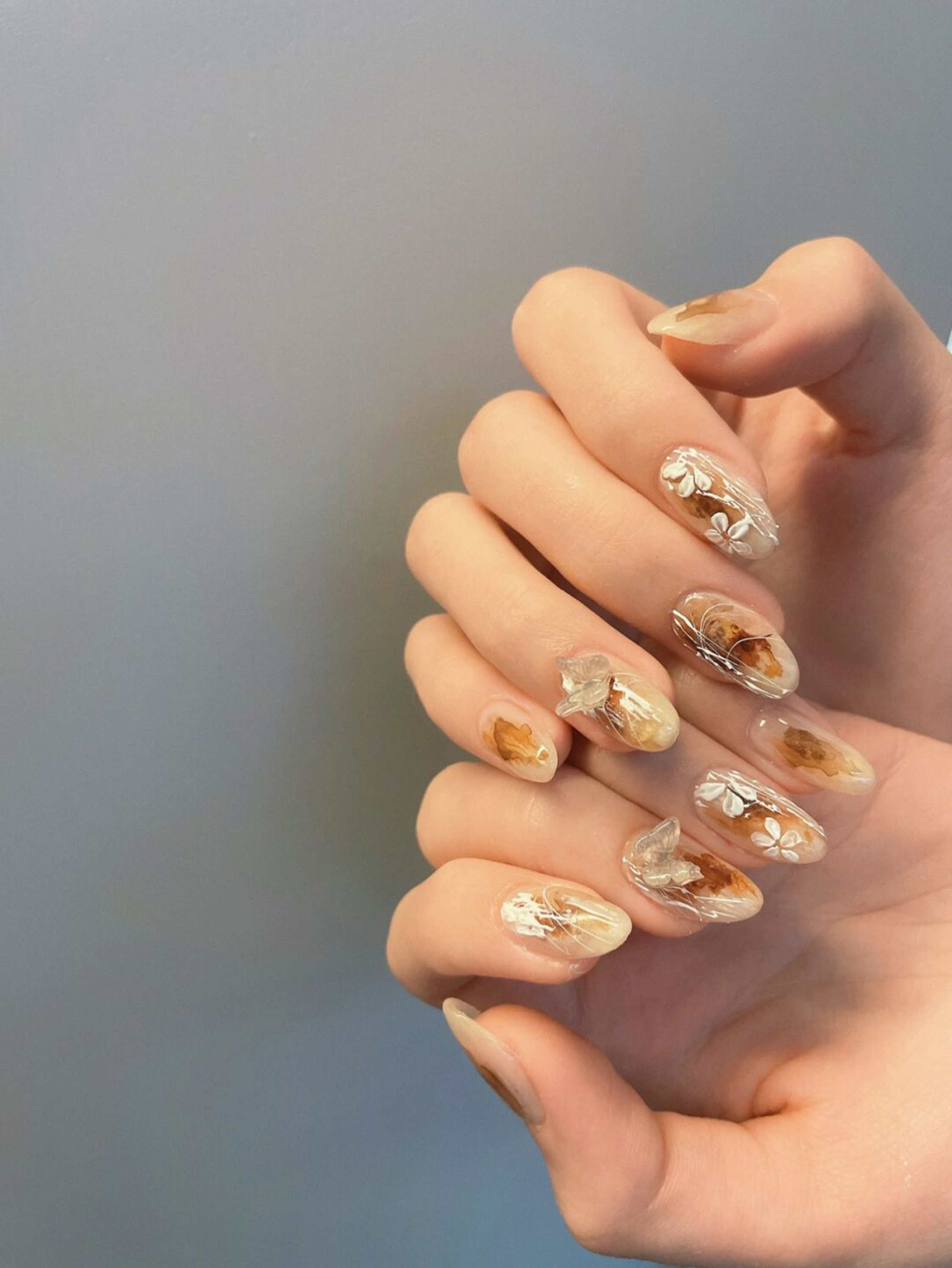 Brown and Nude Floral Almond Nails shown as a nail art design with brown, nude, flower, almond and medium details.