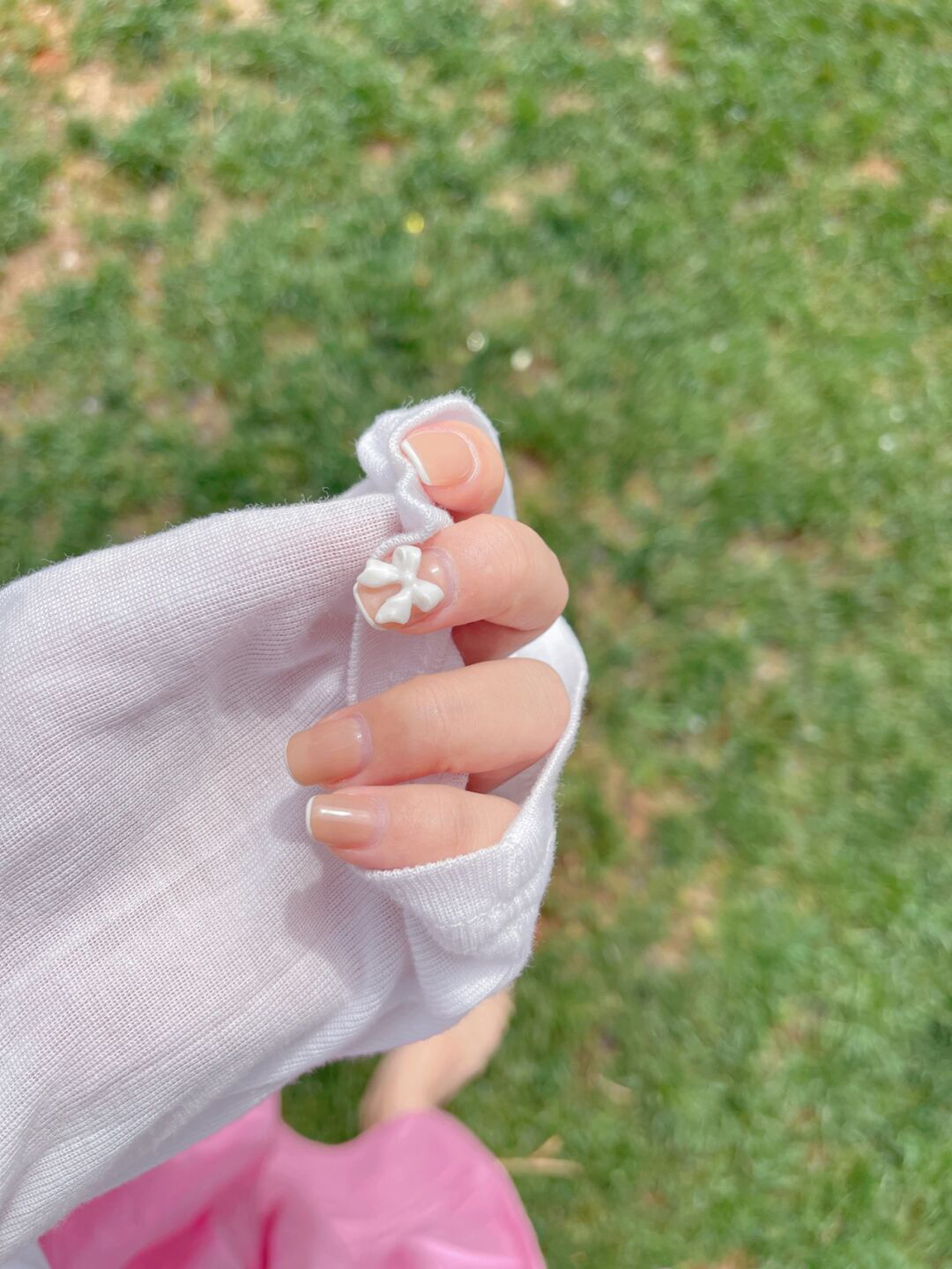 Nude and White Bow Short Nails shown as a nail art design with nude, white, 3d, minimal, bow and short details.