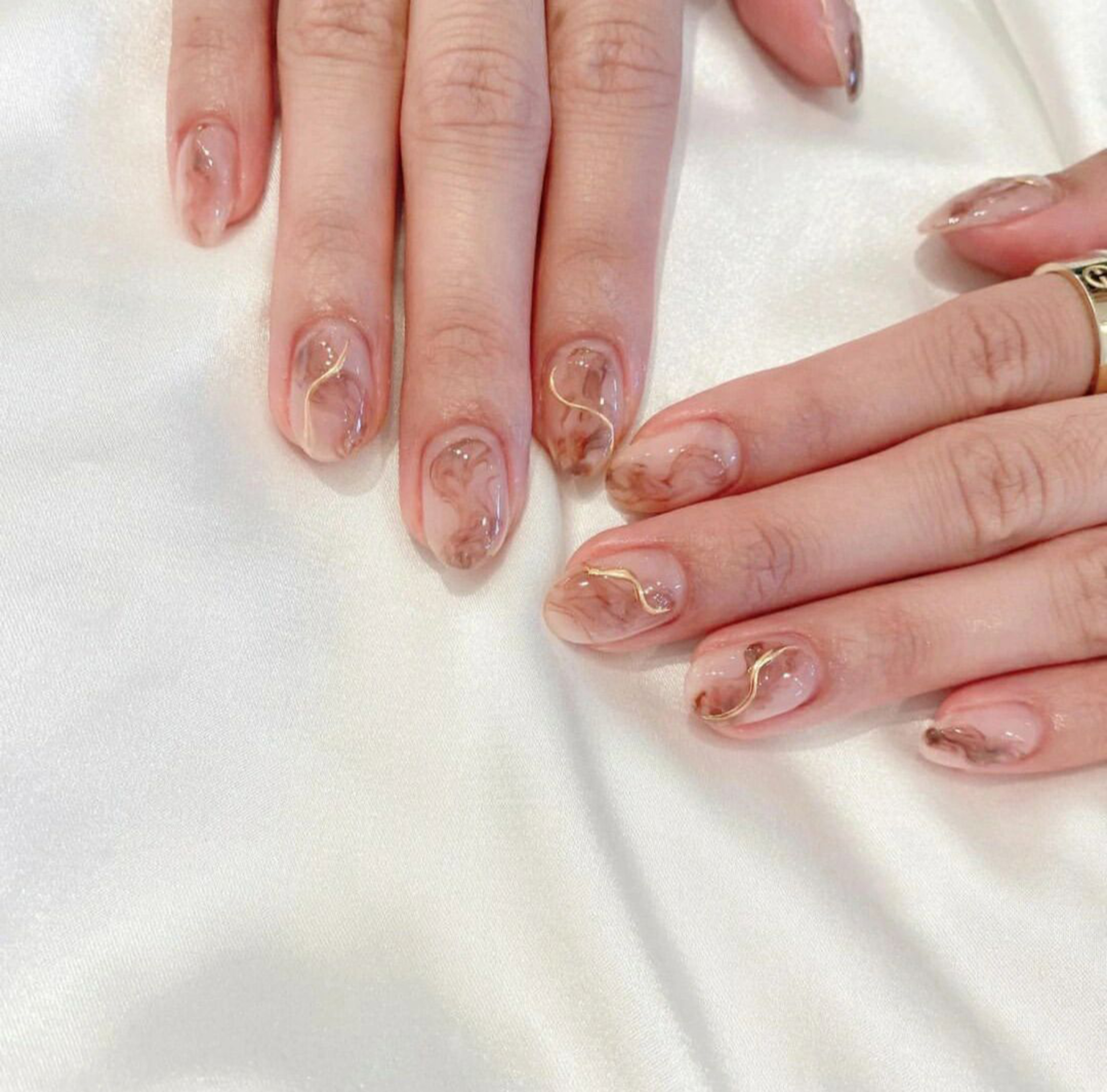 Nude and Gold Abstract Oval Nails shown as a nail art design with nude, gold, marble, elegant, swirl, oval and medium details.