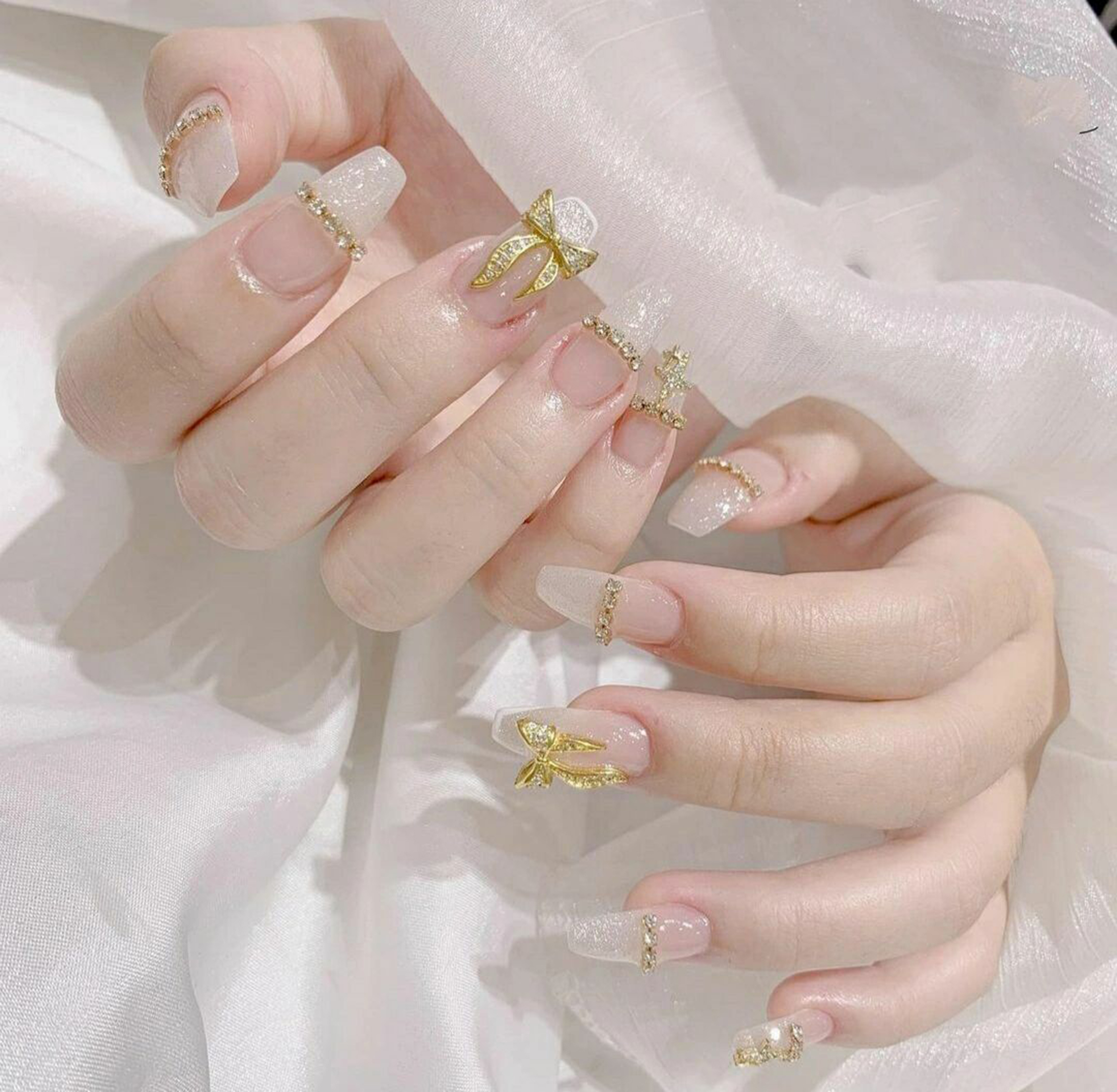 Gold and Nude Bow Long Coffin Nails shown as a nail art design with gold, nude, elegant, 3d, glitter, bow, coffin and long details.